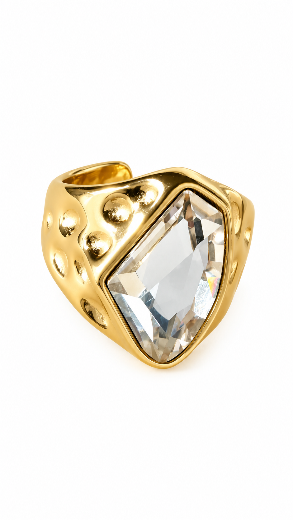 Gouden statement ring met grote transparante steen en brede band met bolvormige details op witte achtergrond