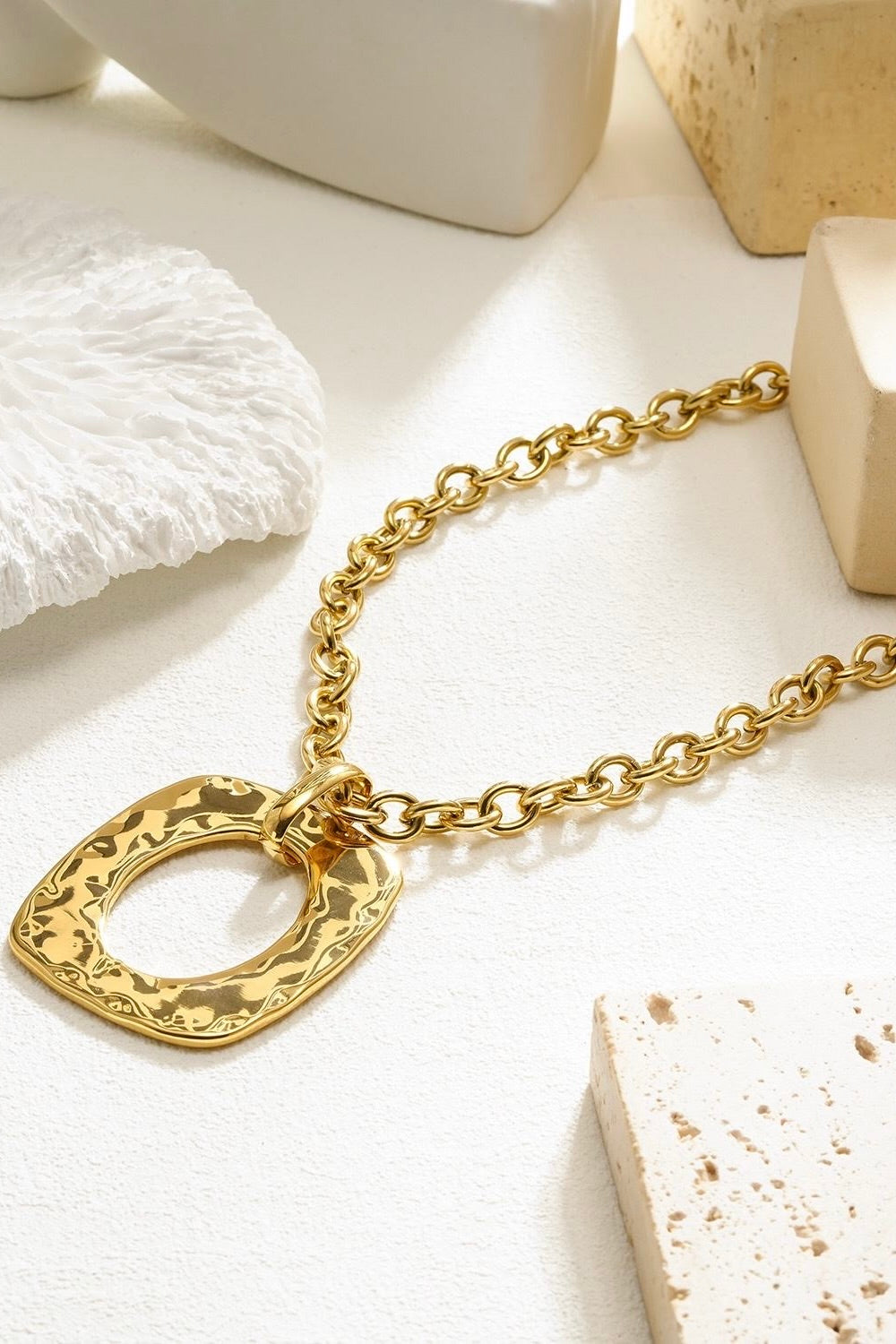 close-up van hals met gouden ketting en opvallende hanger bij wit vest