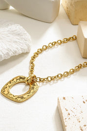 close-up van hals met gouden ketting en opvallende hanger bij wit vest