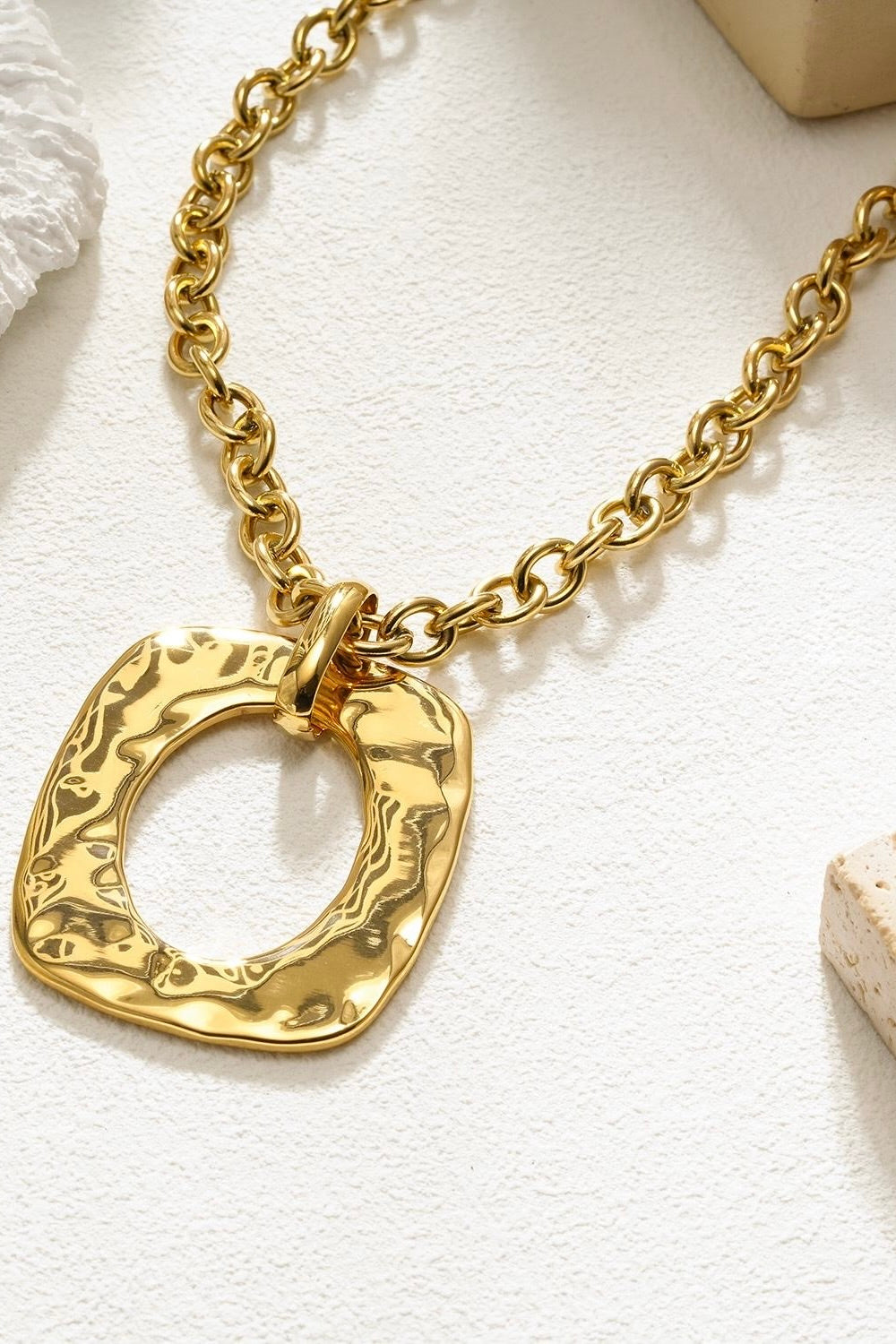 gouden ketting met ovale hanger plat gelegd op witte ondergrond