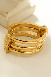 gouden ring met glanzende afwerking en steentjes gefotografeerd op lichte ondergrond