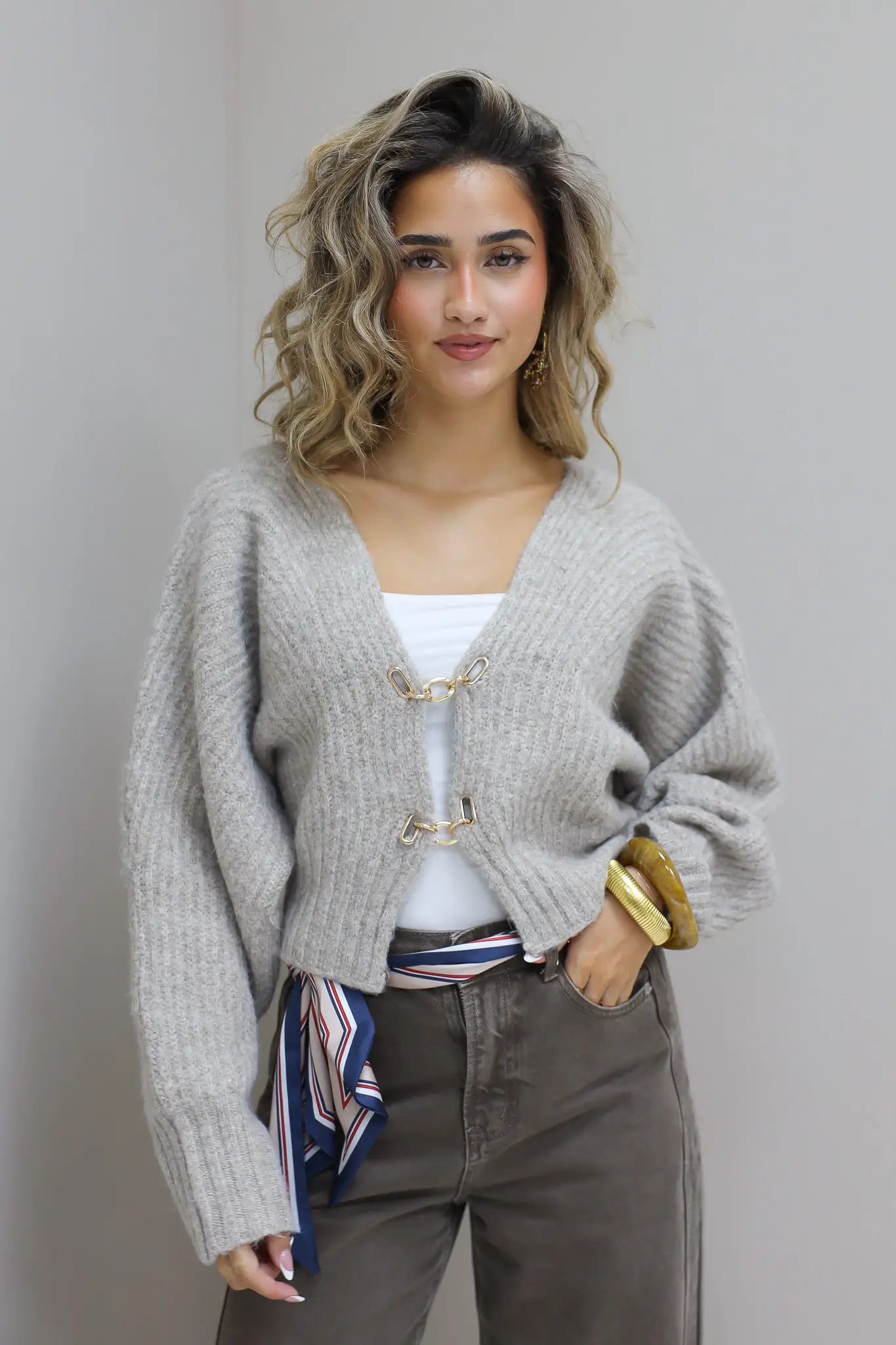 Model staat recht vooruit in studio met grijs vest