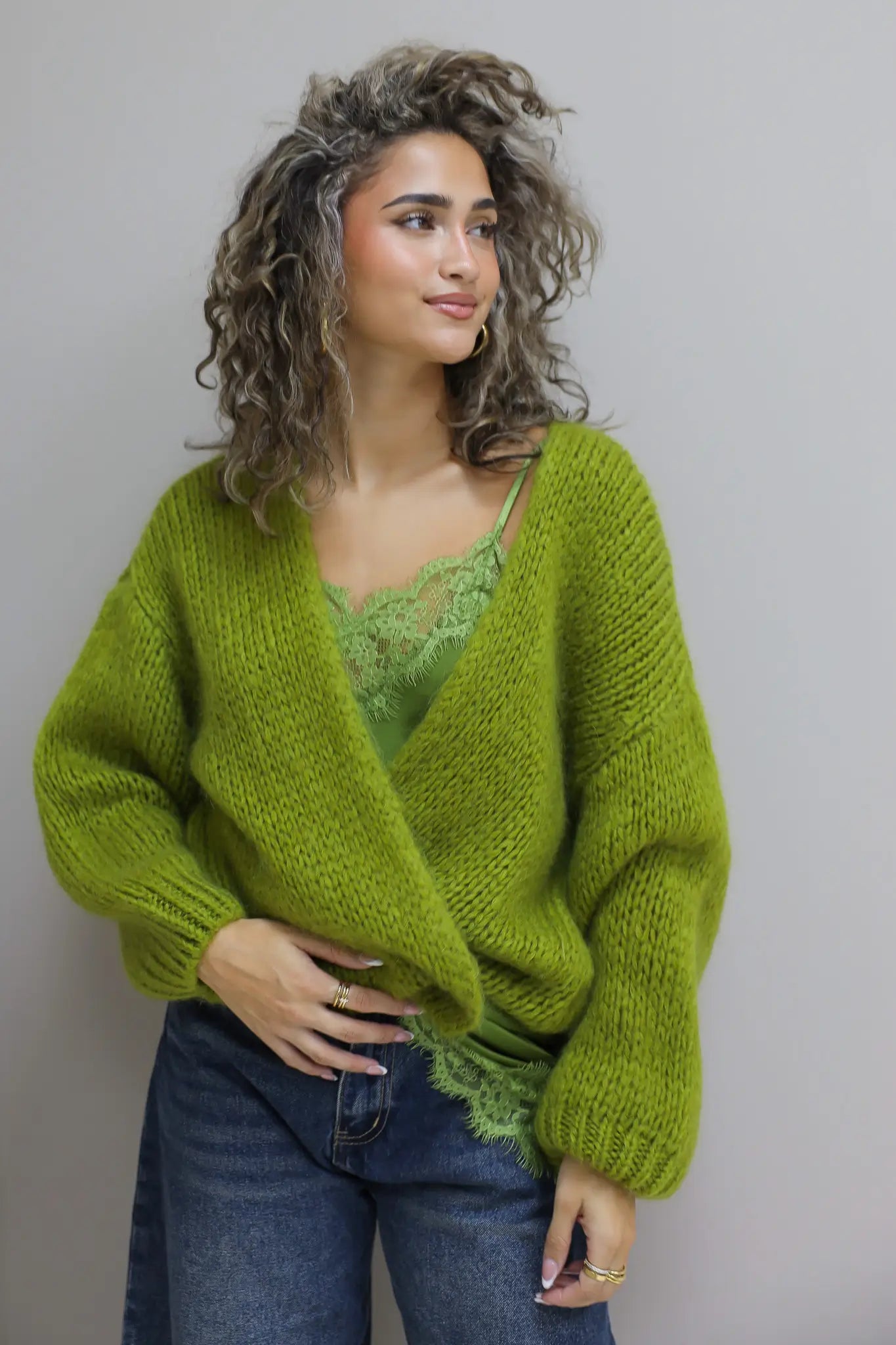 model draagt vest over top met jeans in een ontspannen pose