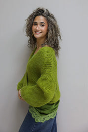 model met gebreid vest in groene tint, top met kant zichtbaar