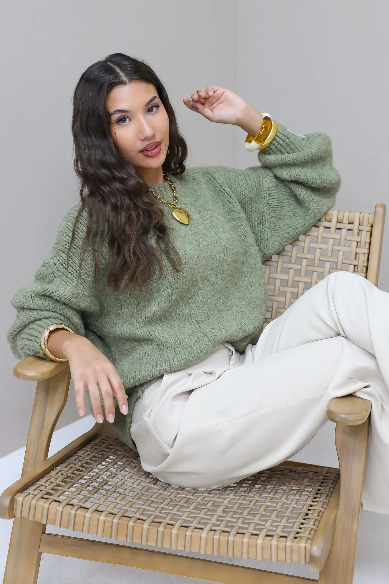 Model draagt groene fluffy trui met blauwe jeans en hakken