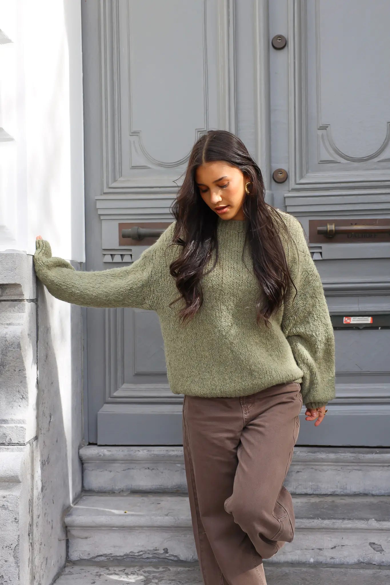 Model loopt op traptreden in groene fluffy trui met bruine broek