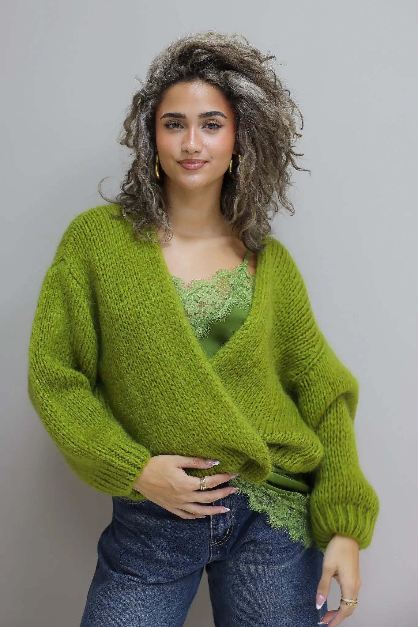 model draagt groene top met kant onder een losvallend vest