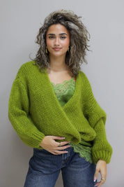 model draagt groene top met kant onder een losvallend vest