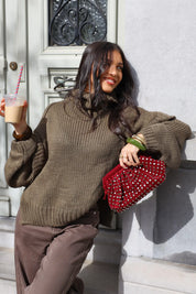 Model leunt tegen een muur met groene trui