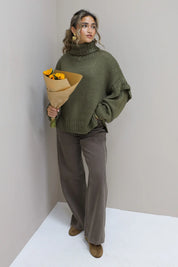 Model poseert recht vooruit met groene trui en bloemen