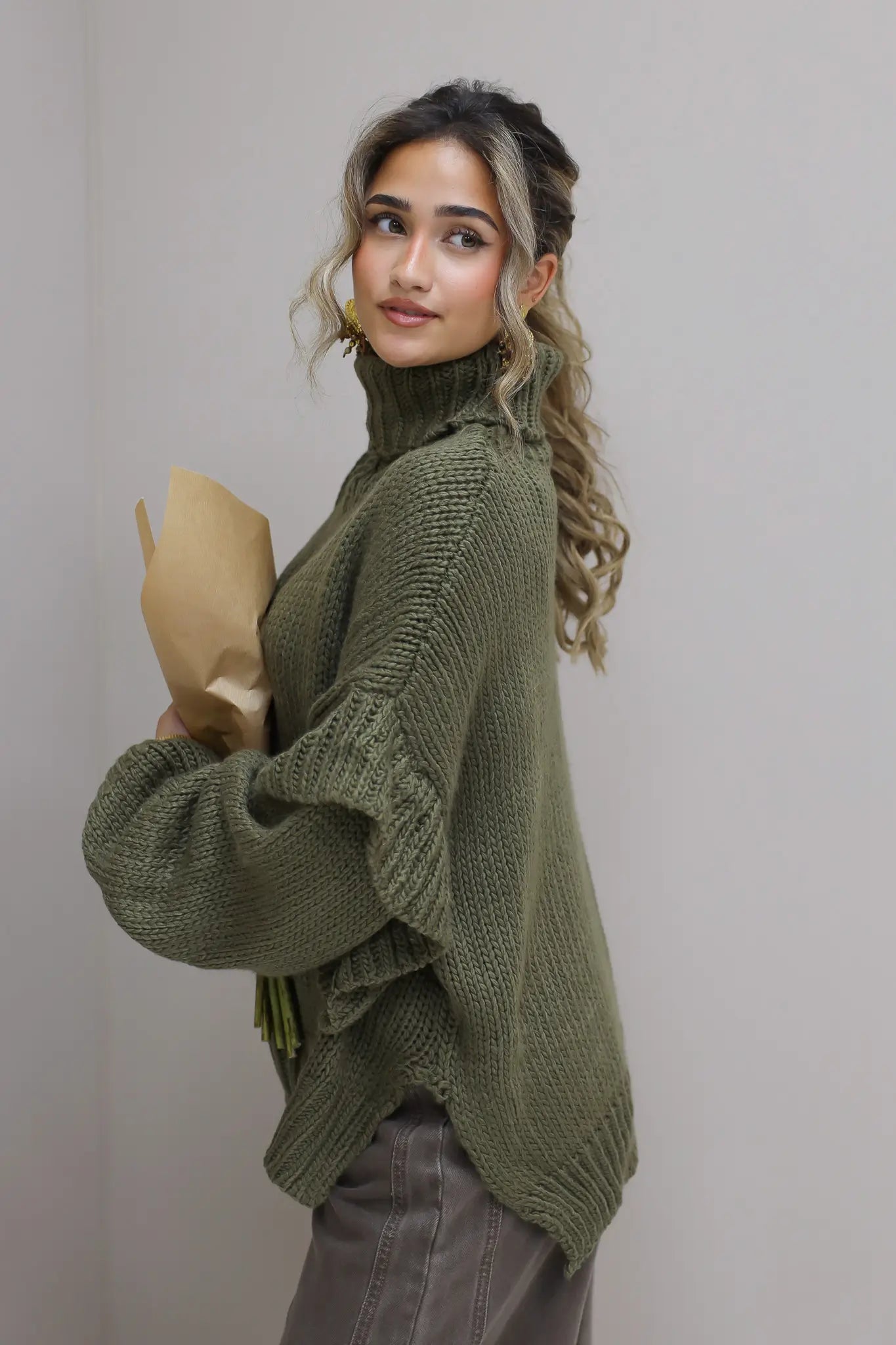 Model houdt zonnebloemen vast met groene trui