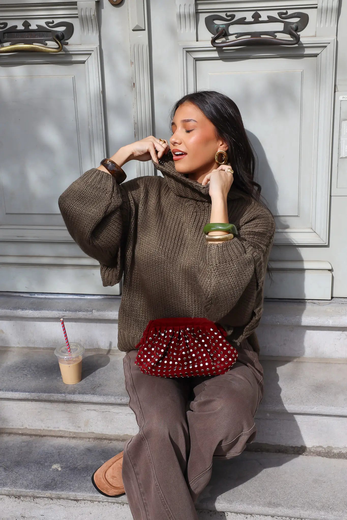 Model drinkt buiten terwijl ze een groene trui draagt