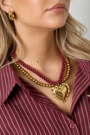 Ketting met rood koord en gouden hart gedragen om de hals