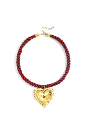 Ketting met rood koord en gouden hart plat gefotografeerd