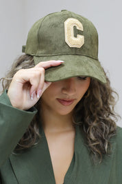 close up van groene honkbalpet met beige letter c gedragen door vrouw