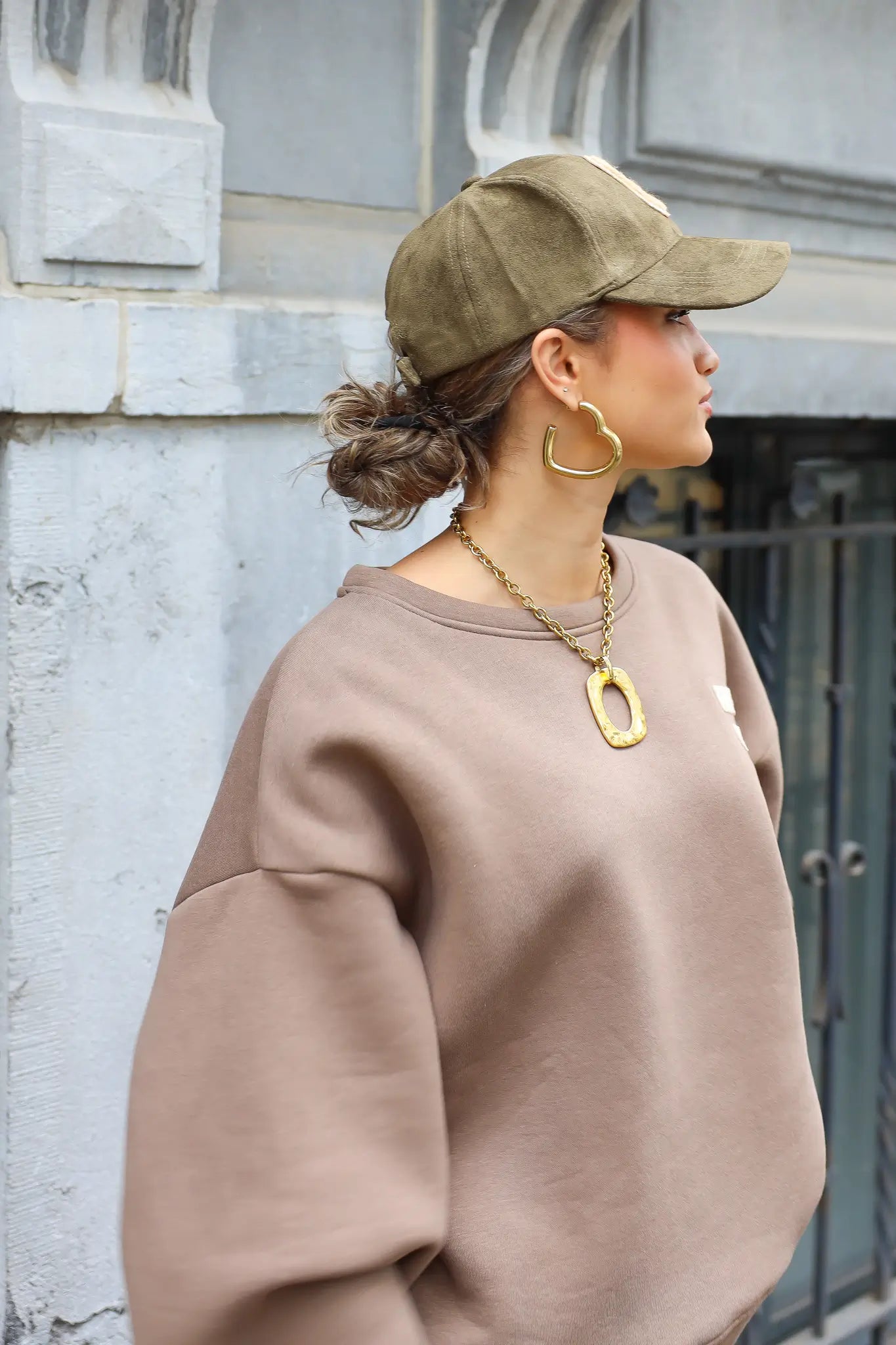 zijaanzicht van vrouw met lage knot die groene honkbalpet met beige letter c draagt