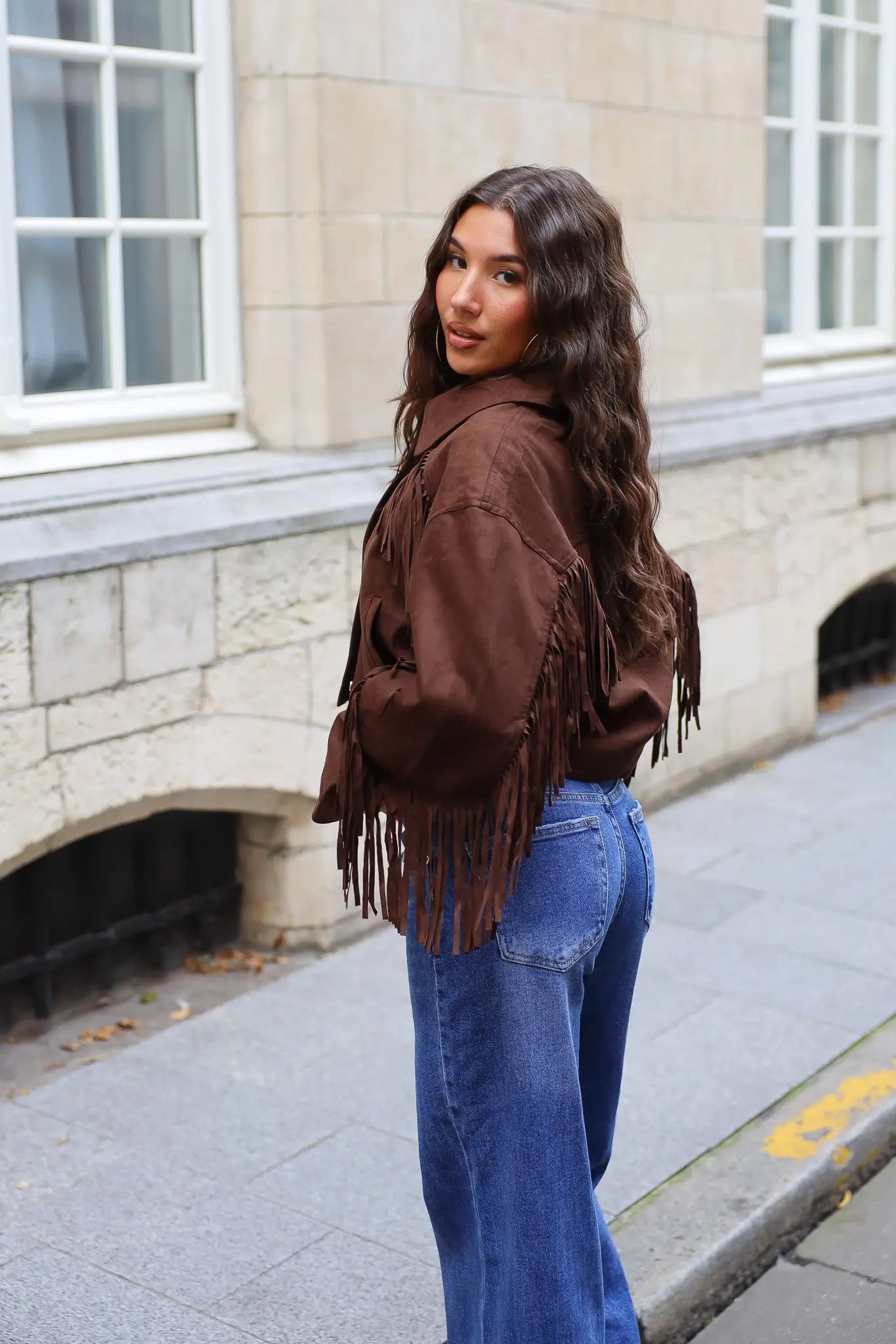 Donkerbruin suède jasje met lange franjes aan de mouwen en blauwe jeans