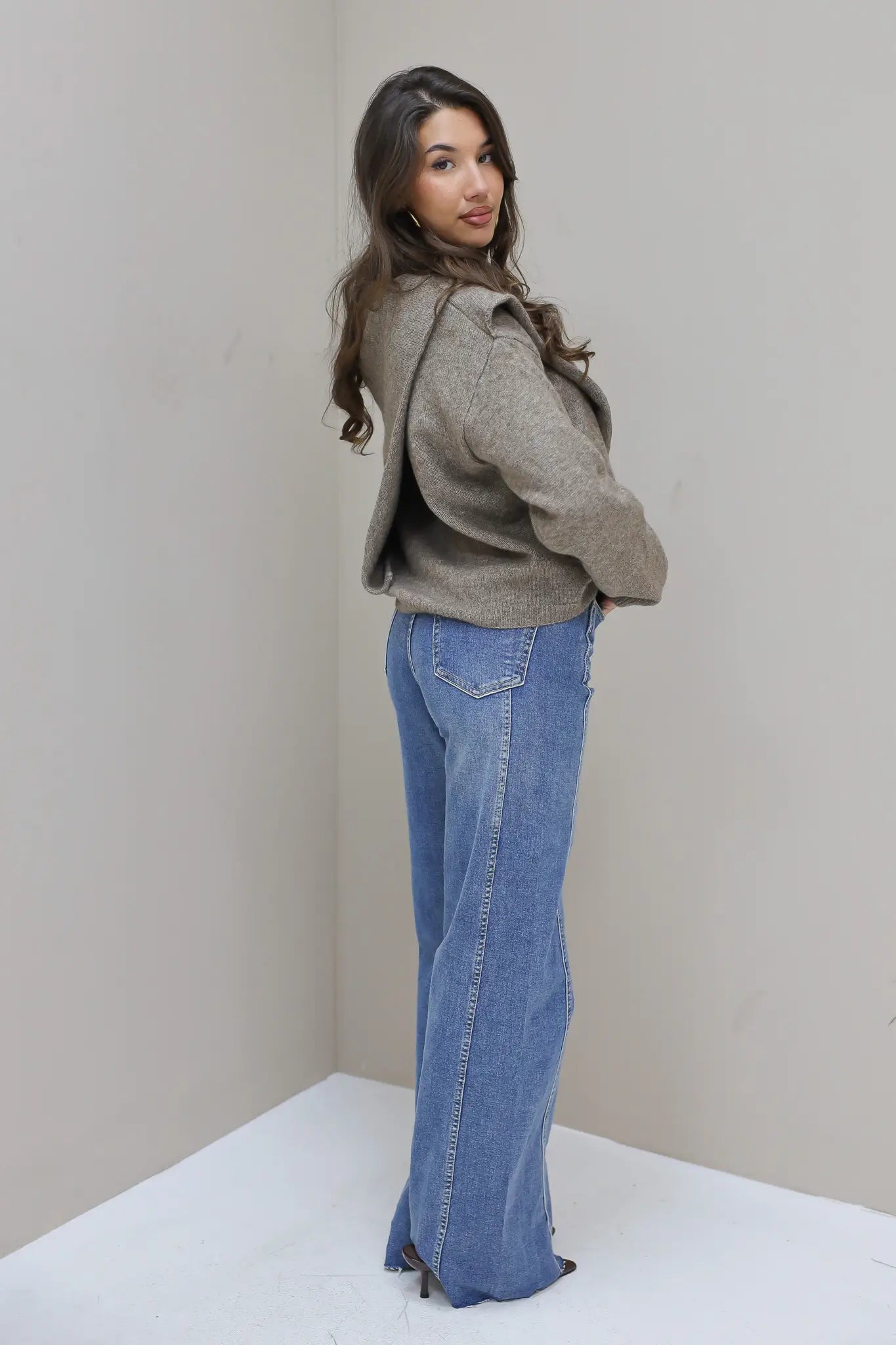 model draagt lichte wide leg jeans met grijze knit