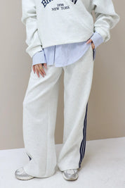 grijze jogger met rechte pijpen en strepen aan de zijkant voorkant