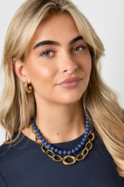 vrouw draagt grove gouden ketting met cirkels bij donkerblauwe top