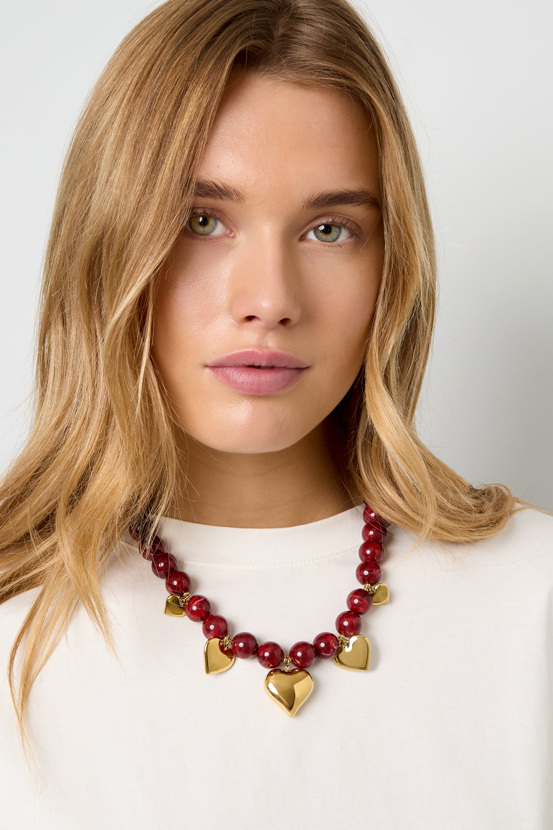 Model draagt de Ketting Kralen Hartjes Bordeaux met glanzende kralen en hartvormige details