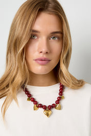 Model draagt de Ketting Kralen Hartjes Bordeaux met glanzende kralen en hartvormige details