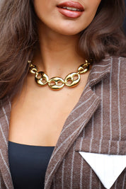 Close-up van de Ketting Luxe Schakels goud om de hals bij een vrouw met blazer