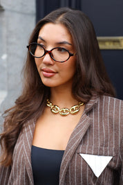 Model met Ketting Luxe Schakels goud, gedragen over een bruine blazer buiten