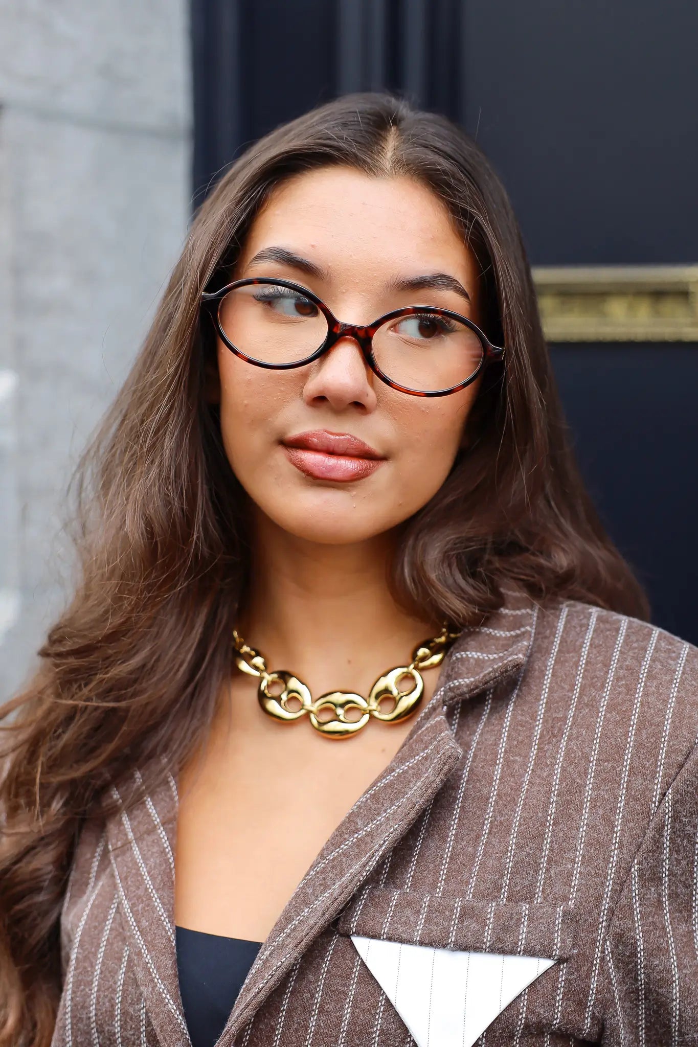 Vrouw met Ketting Luxe Schakels goud, kijkend naar voren met blazer en bril