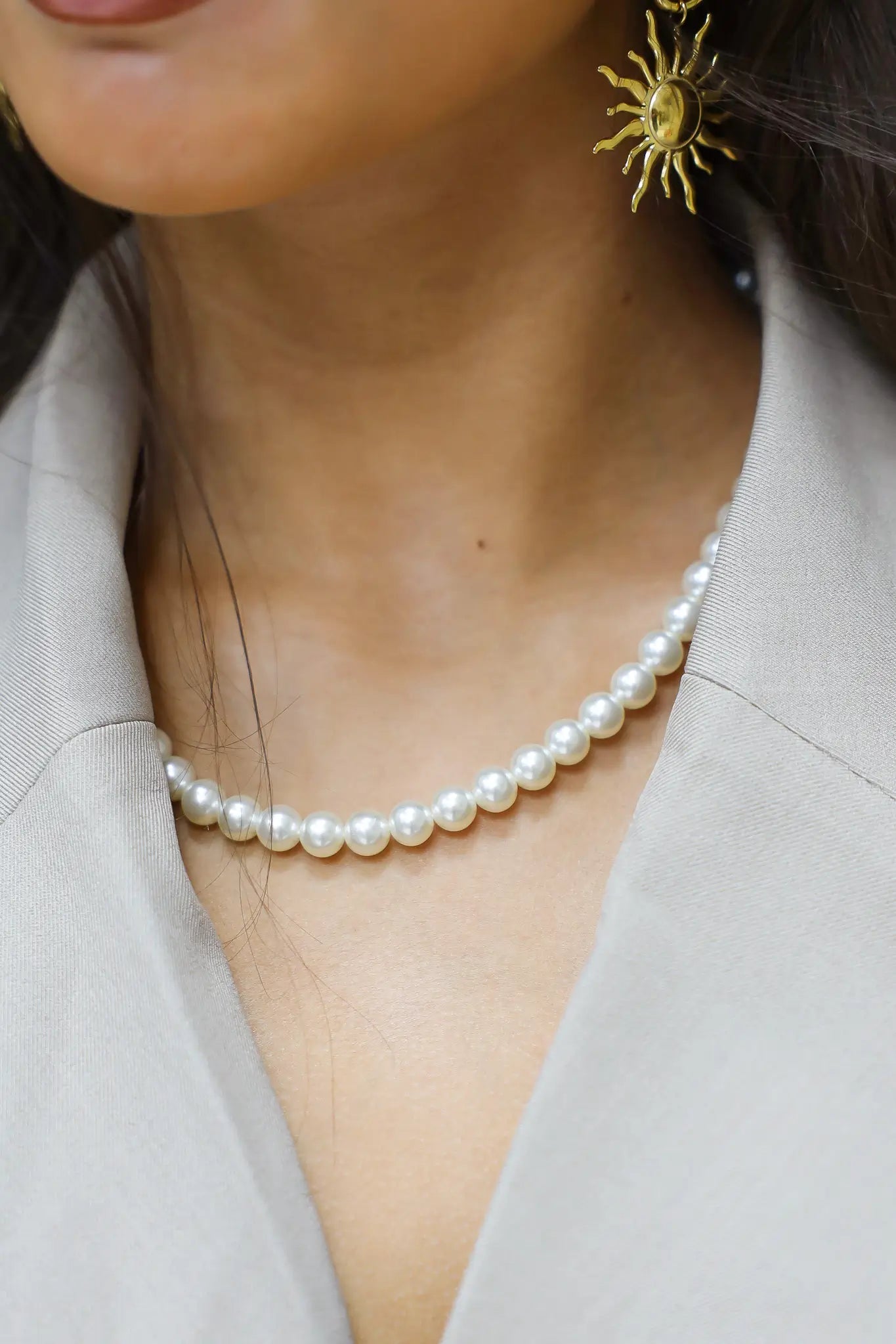 witte parelketting gedragen met lichtgrijze blazer