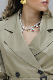 gouden halsketting met parels en bedels gedragen bij beige trenchcoat