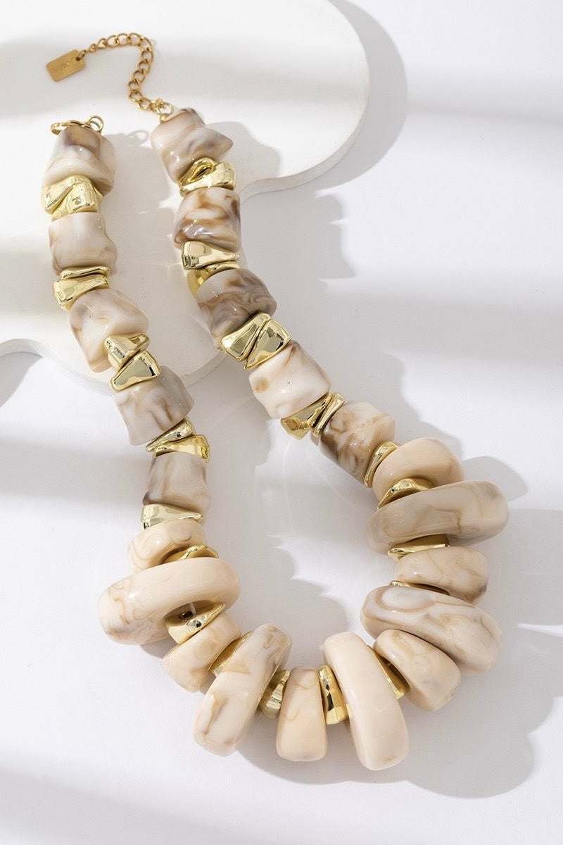 Ketting plastic beige met goudkleurige accenten gefotografeerd