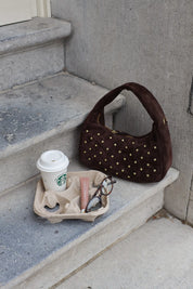 Bruine suède tas met goudkleurige studs op een trap gefotografeerd