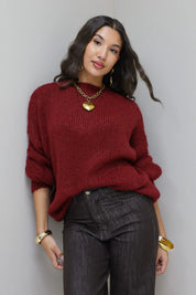 Model draagt de Liva trui bordeaux, licht cropped met gouden sieraden