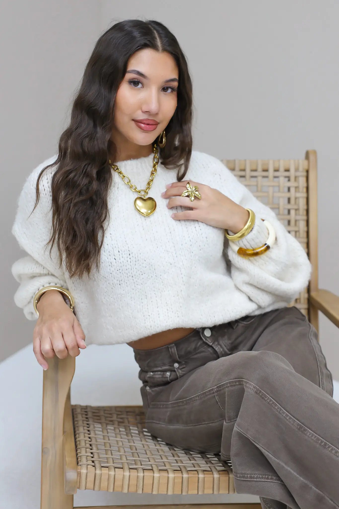 Model met hand in haar draagt de Liva trui wit met bruine broek