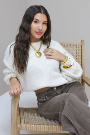 Model met hand in haar draagt de Liva trui wit met bruine broek