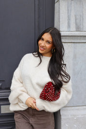 Model lacht in de Liva trui wit met bruine broek en gouden accessoires