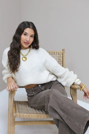 Model in de Liva trui wit met bruine broek en opvallende gouden sieraden