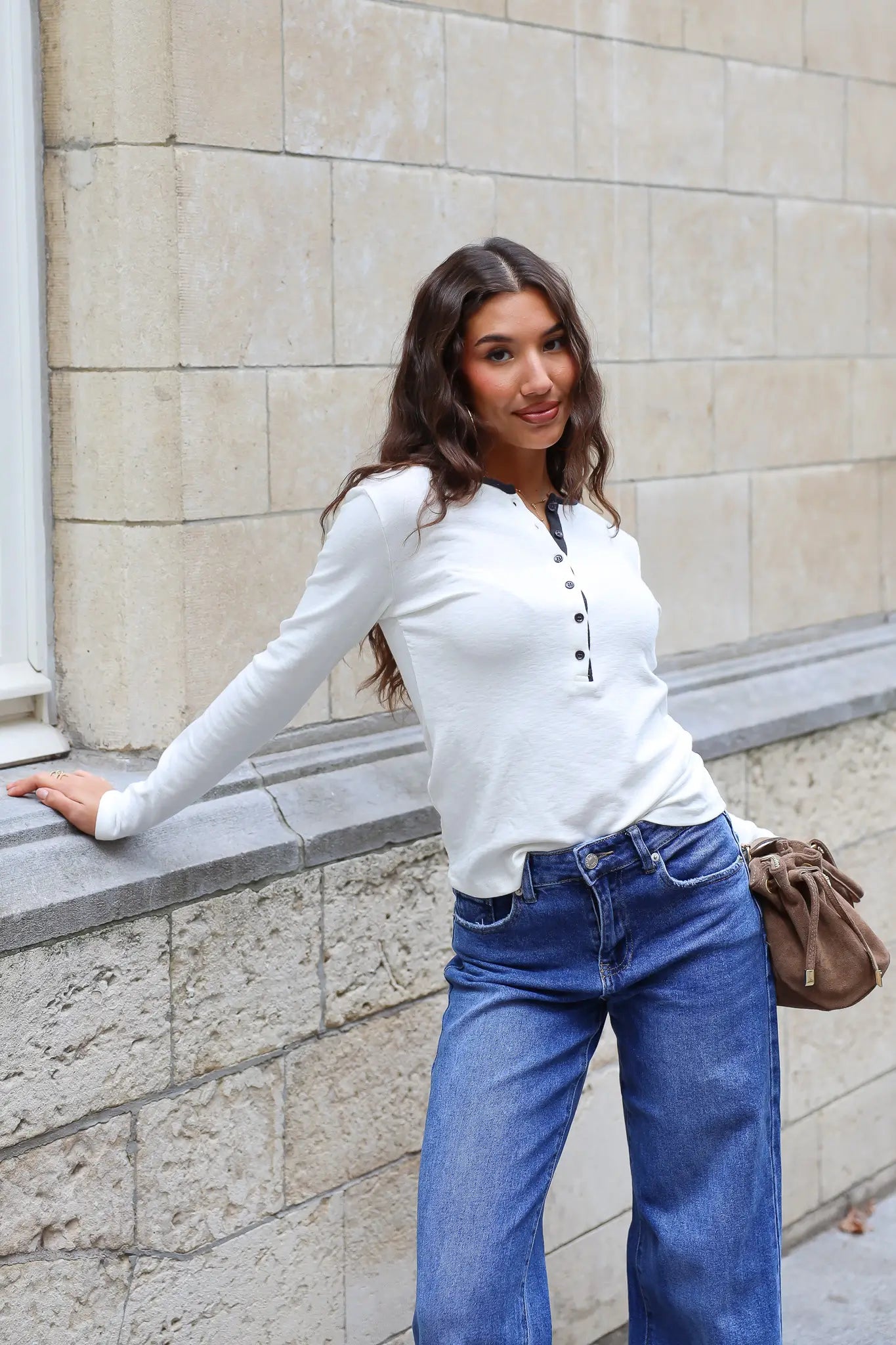 Crème dames longsleeve met ronde hals zwarte bies en kleine zwarte knoopjes gedragen op een blauwe jeans
