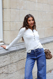 Crème dames longsleeve met ronde hals zwarte bies en kleine zwarte knoopjes gedragen op een blauwe jeans