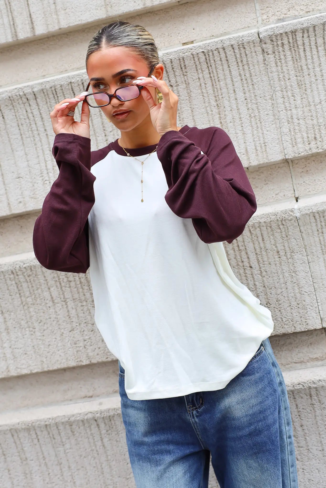 Crème raglan longsleeve met donkerbruine mouwen en ronde hals gedragen met blauwe jeans