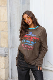 Bruine longsleeve met rode en blauwe tekstprint gecombineerd met zwarte wide leg jeans