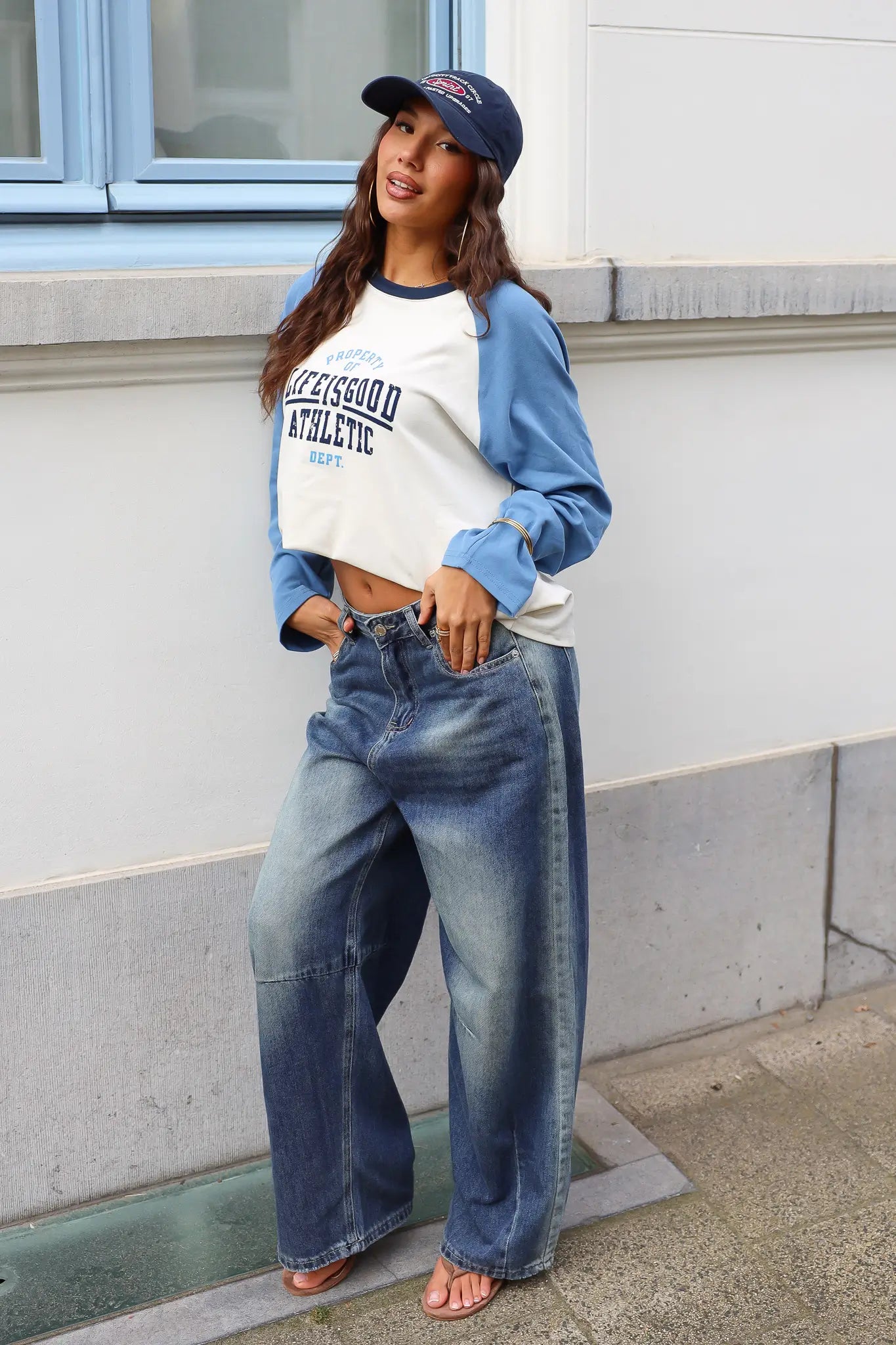 Dames longsleeve Athletic Blauw gecombineerd met een wide leg jeans en donkerblauwe pet