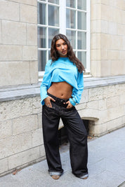 Helderblauw T-shirt met lange mouwen, opgetrokken gestyled met een zwarte jeans en bruine tas