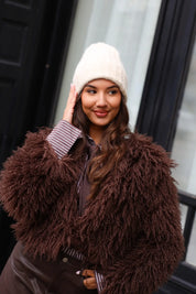 Close-up van model met beige muts en donkere jas