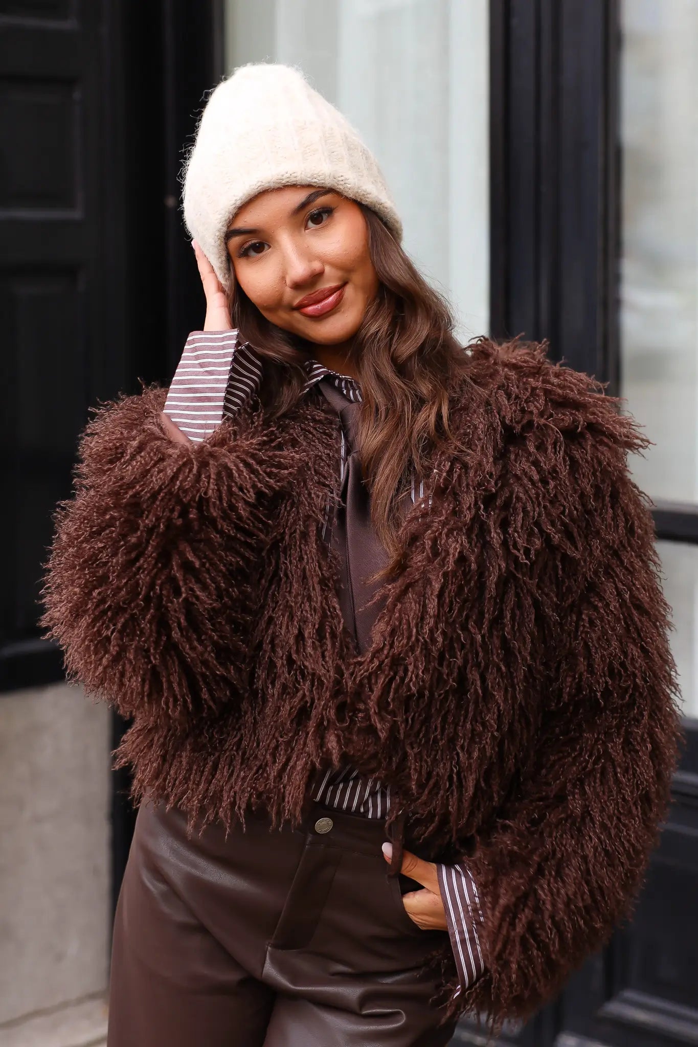 Close-up van beige muts terwijl model zit met tas