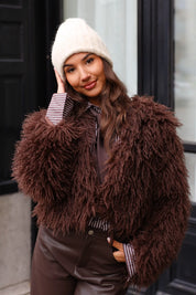 Close-up van beige muts terwijl model zit met tas