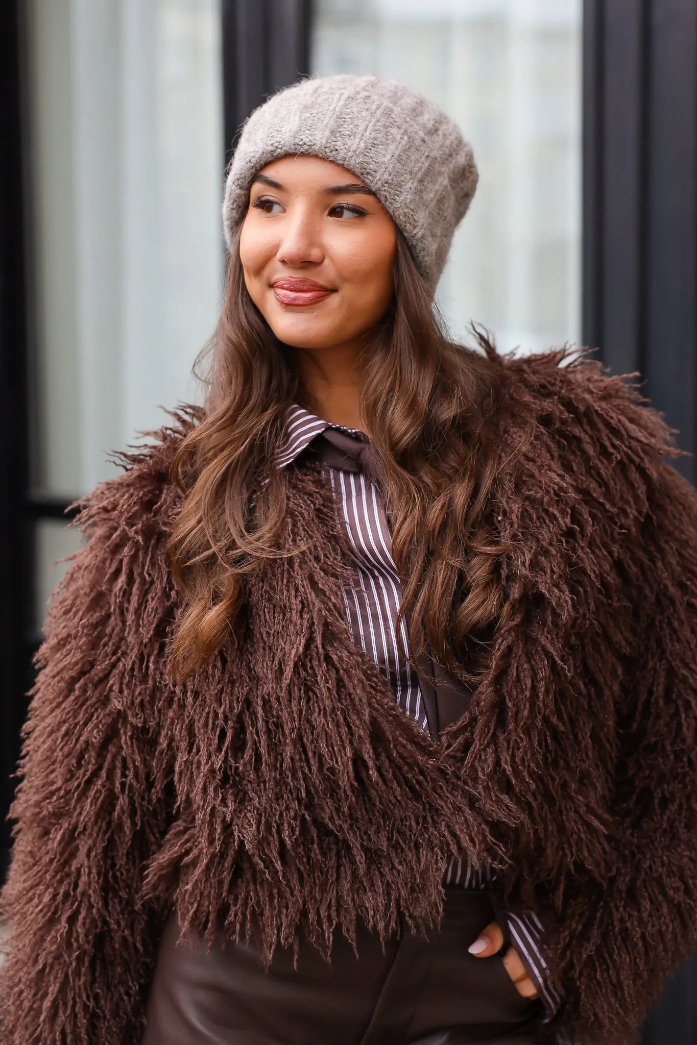 Model met taupe muts kijkt opzij in winterse outfit