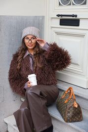 Model met taupe muts en bruine jas volledig in beeld