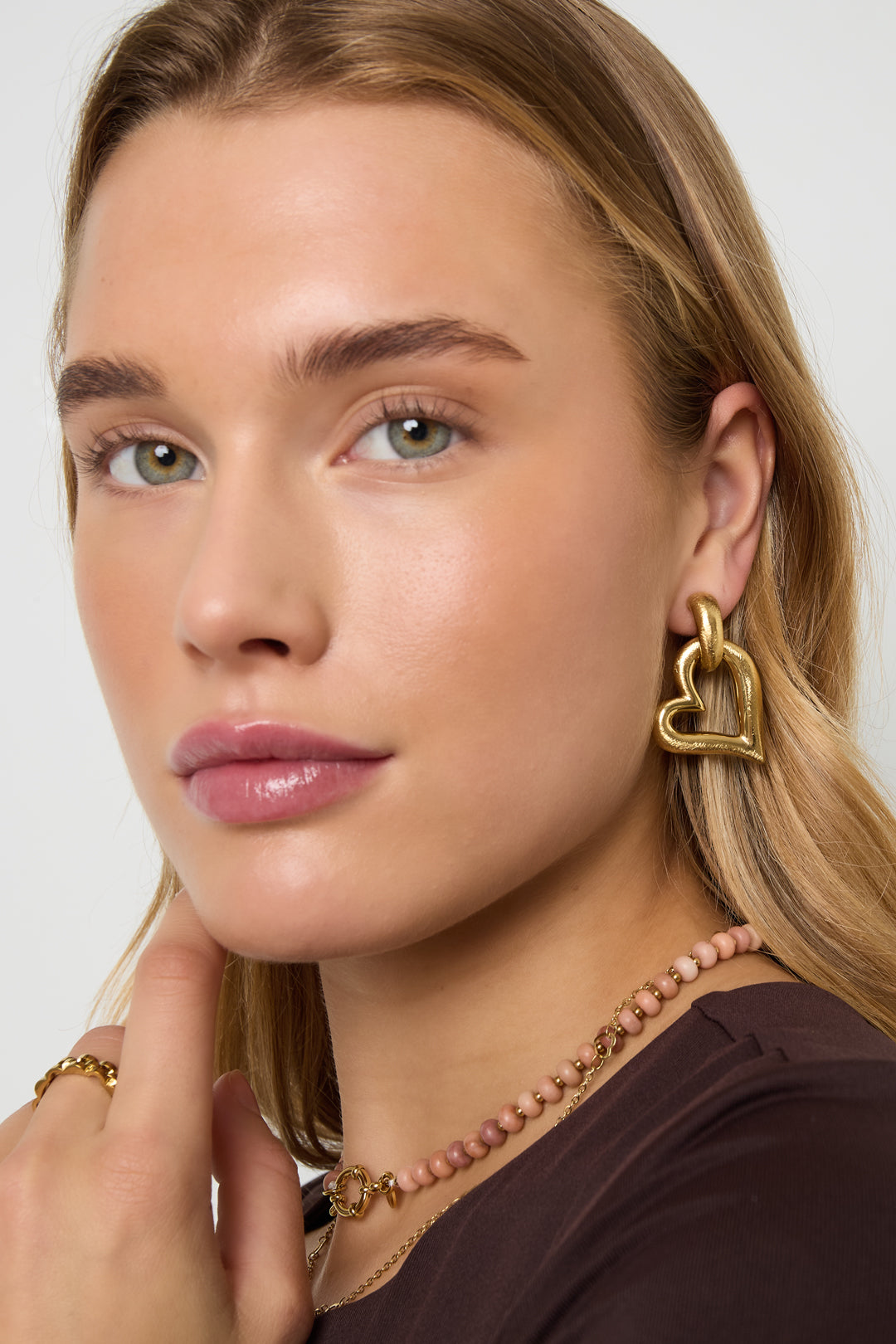 Close-up van model met hangende hartvormige gouden oorbellen